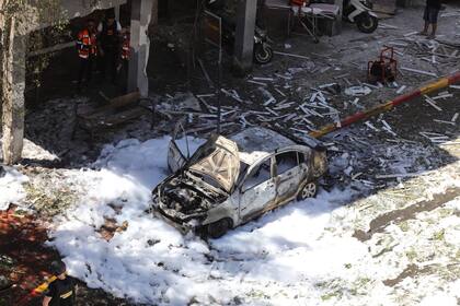 Un automóvil quemado frente a una casa dañada que fue alcanzada por un cohete disparado por el movimiento islamista palestino Hamas desde Gaza hacia Israel
