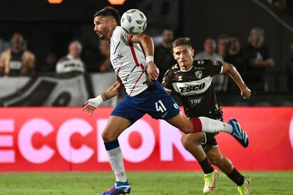 Iván Leguizamón, de escaso aporte ofensivo, parece llevarse la pelota con un brazo, mientras es seguido por Sasha Marcich; el balón va por un lado, y San Lorenzo, por otro.