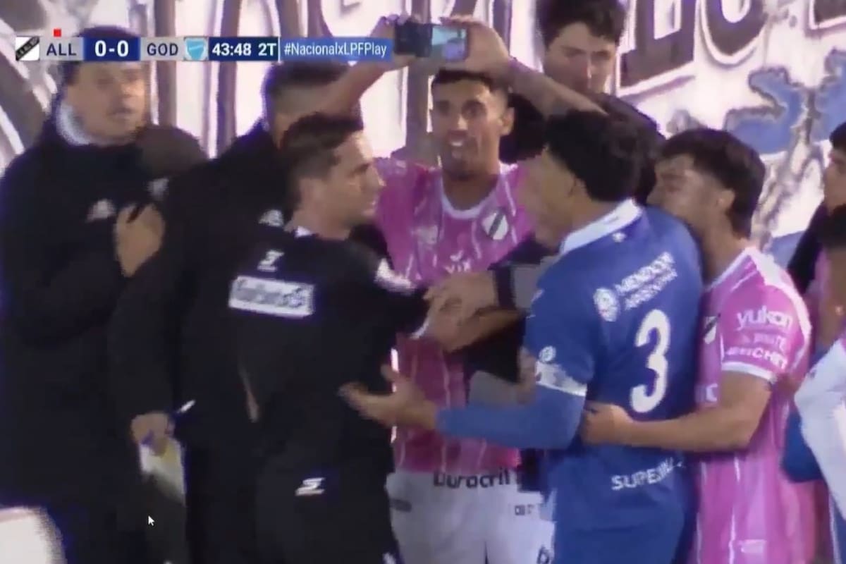 Iván Zafarana, de All Boys, le muestra el celular a Nicolás Lamolina mientras le dice: "Fue afuera"; el árbitro había cobrado penal para Godoy Cruz, pero modificó el fallo