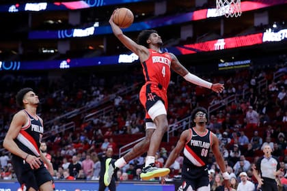 Jalen Green (4), de los Rockets de Houston, clava el balón entre Rayan Rupert, izquierda, y Scoot Henderson (00), de los Trail Blazers de Portland, durante la segunda mitad del juego de baloncesto de la NBA, el lunes 25 de marzo de 2024, en Houston. (AP Foto/Michael Wyke)