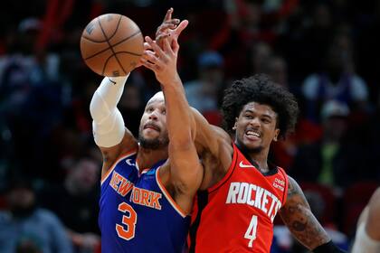 Jalen Green (4), de los Rockets de Houston, mete la mano para interponerse en un pase que buscaba las manos de Josh Hart (3), de los Knicks de Nueva York, durante la segunda mitad del juego de baloncesto de la NBA, el lunes 12 de febrero de 2024, en Houston. (AP Foto/Michael Wyke)