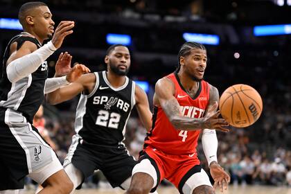 Jalen Green (4) de los Rockets de Houston realiza un pase mientras es defendido por Malaki Branham (22) y Keldon Johnson, ambos de los Spurs de San Antonio durante la segunda mitad del juego de baloncesto de la NBA, el lunes 28 de octubre de 2024, en San Santonio. (AP Foto/Darren Abate)