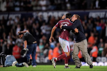 James Tomkins, jugador de West Ham, es sujetado por un hincha en uno de los duelos más recordados, por los violentos enfrentamientos entre simpatizantes de ambos equipos, con lanzamiento de ladrillos y botellas y la intervención de la policía antidisturbios