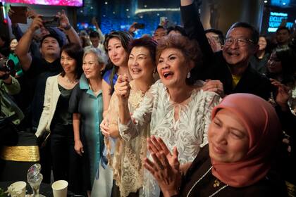 Janet Yeoh, segunda de derecha a izquierda, madre de Michelle Yeoh, celebra después de que su hija ganó el Oscar a mejor actriz en la 95a edición de los Premios de la Academia en Los Angeles, en un evento en un cine de Kuala Lumpur, Malasia, el lunes 13 de marzo de 2023. (Foto AP/Vincent Thian)