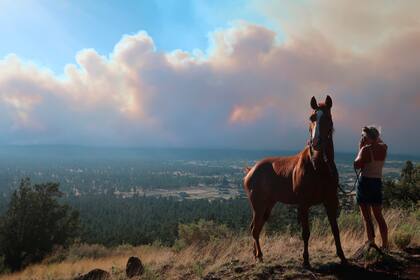 Janetta Kathleen y su caballo, Squish, miran mientras el humo se eleva sobre los vecindarios a las afueras de Flagstaff, Arizona, el domingo 12 de junio. Las autoridades ordenaron evacuaciones por un incendio forestal. (AP foto/Felicia Fonseca)
