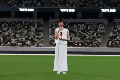 La nadadora japonesa Rikako Ikee, en el Estadio Nacional de Tokio vacío y con la linterna que contiene la llama olímpica.
