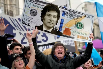 Javier Milei, en campaña, muestra un cartel con un billete de cien dólares con su cara