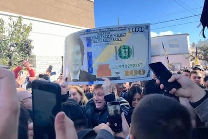 Javier Milei en plena campaña electoral junto a un billete de dólar con su cara.