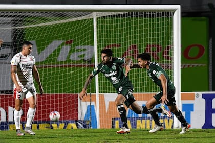 Javier Toledo festeja el gol del 1-1 para Sarmiento contra Newell's, por la Copa de la Liga Profesional; lo sufren Armando Méndez y Julián Fernández, en Junín.