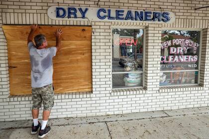 Jay McCoy cubre las ventanas de su negocio con madera en anticipación a la llegada del huracán Milton, el lunes 7 de octubre de 2024, en New Port Richey, Florida. (AP Foto/Mike Carlson)