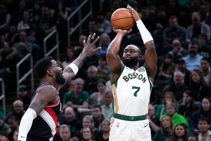 Jaylen Brown (7), de los Celtics de Boston, toma un tiro sobre Deandre Ayton, izquierda, de los Trail Blazers de Portland, durante la primera mitad del juego de baloncesto de la la NBA, el domingo 7 de abril de 2024, en Boston. (AP Foto/Charles Krupa)