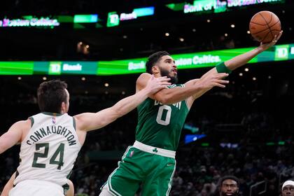 Jayson Tatum (0) de los Celtics de Boston anota frente a Pat Connaughton (24) de los Bucks de Milwaukee, el lunes 13 de diciembre de 2021. (AP Foto/Charles Krupa)
