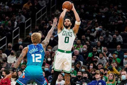 Jayson Tatum (0), de los Celtics de Boston, dispara sobre Kelly Oubre Jr. (12), de los Hornets de Charlotte, durante la primera mitad del juego de la NBA, el miércoles 2 de febrero de 2022, en Boston. (AP Foto/Steven Senne)