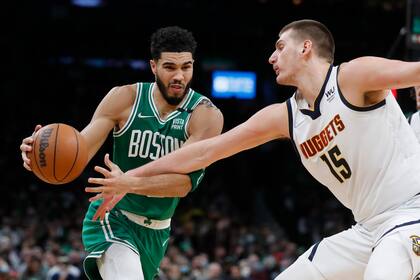 Jayson Tatum (0), de los Celtics de Boston, encara a Nikola Jokic (15), de los Nuggets de Denver, durante la primera mitad del juego de la NBA del viernes 11 de febrero de 2022, en Boston. (AP Foto/Michael Dwyer)