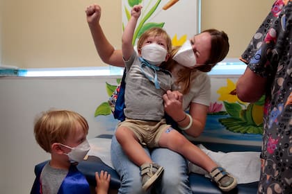 Jen Maddock y su hijo Will, de 23 meses, levantan los puños en celebración después que el pequeño recibió la vacuna contra el Covid-19 en Southwest Pediatrics en St. Louis. (Robert Cohen/St. Louis Post-Dispatch vía AP)