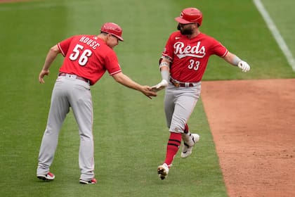 Jesse Winker de los Rojos de Cincinnati es felicitado por el coach de tercera base J.R. House tras conectar un cuadrangular en la novena entrada del juego ante los Cardenales de San Luis el domingo 6 de junio del 2021. (AP Photo/Jeff Roberson)