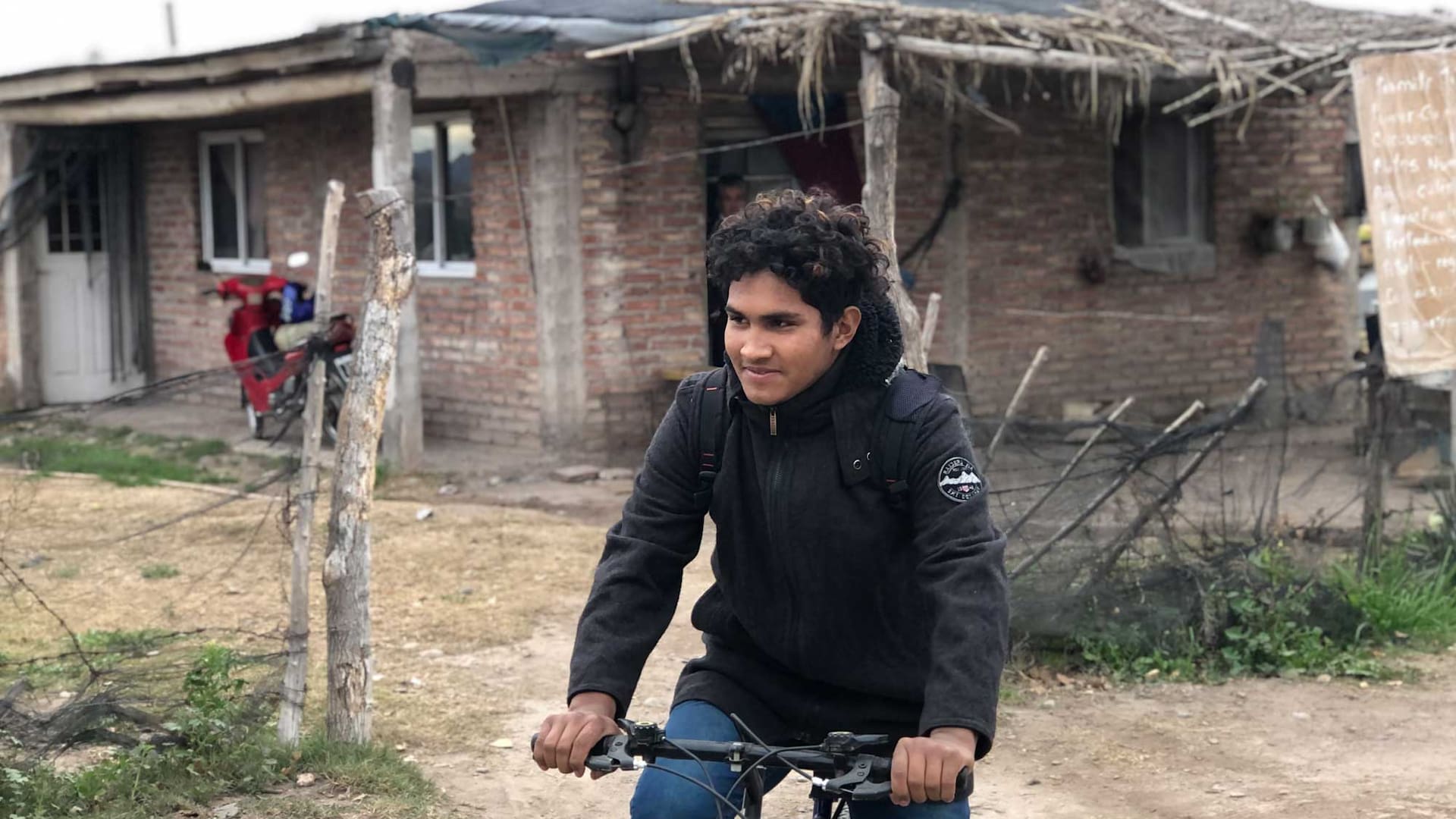 Jesús subiéndose a la bicicleta para ir a la escuela. Está necesitando una moto para poder recorrer más rápido los 14 kilómetros que lo separan de su escuela