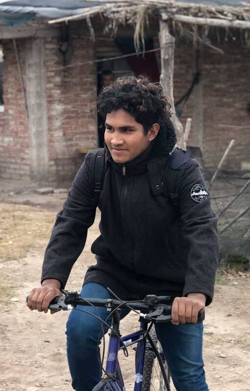 Jesús subiéndose a la bicicleta para ir a la escuela. Está necesitando una moto para poder recorrer más rápido los 14 kilómetros que lo separan de su escuela