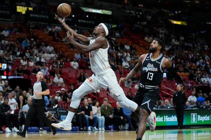Jimmy Butler (22), del Heat de Miami, busca el aro frente a la marca de Paul George (13),de los Clippers de Los Ángeles, durante al primera mitad del partido de la NBA en Miami, el jueves 8 de diciembre de 2022. (AP Foto/Wilfredo Lee)