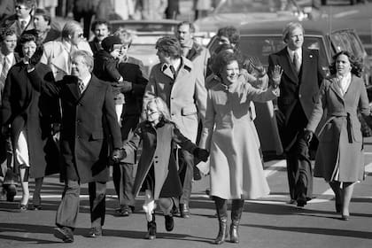 Jimmy y Rosalynn Carter se dan la mano de su hija, Amy, mientras caminan por Pennsylvania Avenue durante su desfile inaugural en Washington, el 20 de enero de 1977. Carter se convirtió en el primero en recorrer a pie más de una milla en el ruta a la Casa Blanca