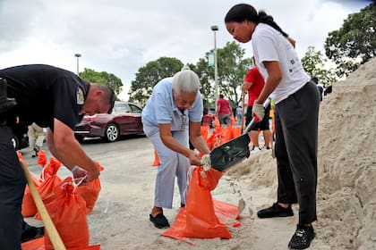 Joang Chang recibe ayuda al cargar sus bolsa de arena, en Margate, Florida