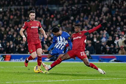 Joao Pedro, de Brighton y Hove Albion, es marcado por Nelson Semedo, de Wolverhampton Wanderers, derecha, en la batalla por el balón durante el partido de fútbol de la Liga Premier inglesa entre Brighton y Hove Albion y Wolverhampton Wanderers en el American Express Stadium, Brighton, Inglaterra, el lunes 22 de enero de 2024. (Adam Davy/PA vía AP)