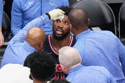 Joel Embiid, pívot de los 76ers de Filadelfia, recibe atención tras sufrir un golpe en el rostro durante el sexto partido de la serie de playoffs ante los Raptors de Toronto, el jueves 28 de abril de 2022 (Nathan Denette/The Canadian Press via AP)