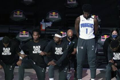 John Isaac, de Orlando Magic, sin la camiseta de Orlando Magic y parado, en medio de sus compañeros