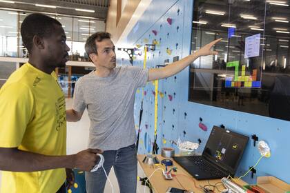 Joktan Willem, a la derecha, profesor del Campus de Innovación Deportiva en Brujas, Bélgica, le enseña a Nehemie Kasongay Diakiesse cómo diseñar videojuegos que hagan que los usuarios hagan ejercicio