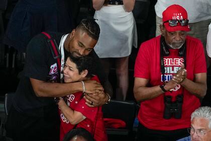 Jonathan Owens, esposo de la gimnasta de los Estados Unidos, Simone Biles, abraza a su madre Nellie Biles, mientras es condecorada con la medalla de oro durante las finales del all-around de la Gimnasia Artística Femenina, en el Bercy Arena, en París, Francia. (AP Foto/Morry Gash)