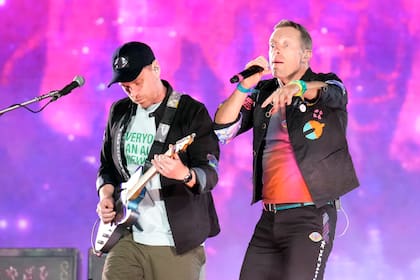 Jonny Buckland, a la izquierda, y Chris Martin de Coldplay durante un concierto de su gira mundial "Music of the Spheres" el jueves 12 de mayo de 2022 en el State Farm Stadium en Glendale, Arizona. La banda incluyó en la gira bicicletas estacionarias y pistas de baile que almacenan y usan la energía de los fans para ayudar a propulsar el espectáculo como parte de un esfuerzo para hacer la gira más ecológica. (Foto de Rick Scuteri/Invision/AP)