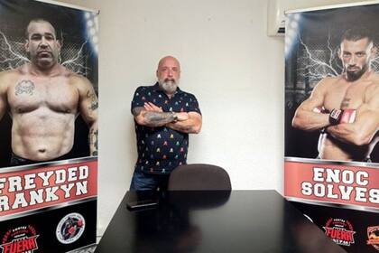 Jorge Fe posa entre la foto de dos de sus empleados.