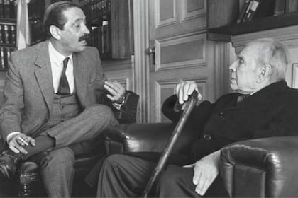 Jorge Luis Borges dialoga con Julio César Strassera , fiscal en el histórico Juicio a las Juntas Militares, minutos antes de asistir a una de las audiencias públicas del proceso judicial.
Foto en papel, 22 de julio 1985.