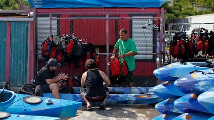 Jose Figueroa (derecha) limpia kayaks con la ayuda de dos compañeros, en la bahía Fajardo, en Puerto Rico