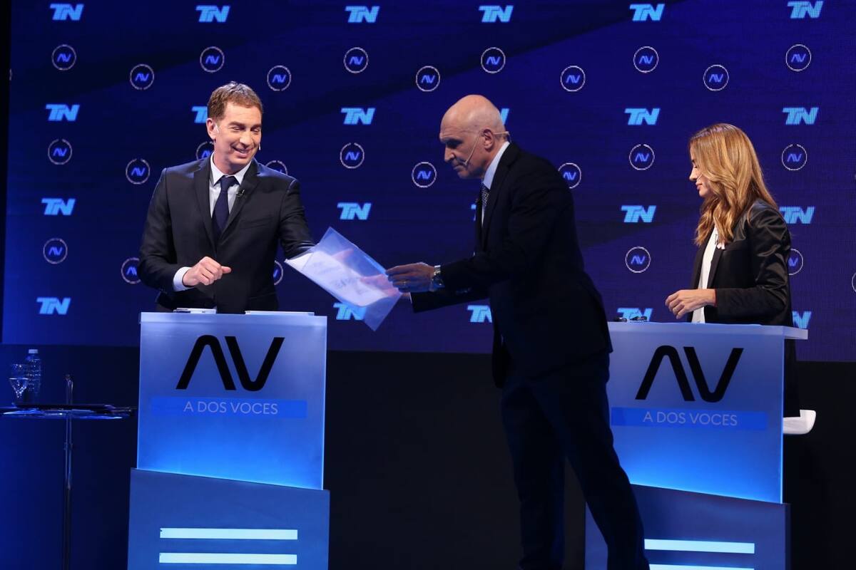 José Luis Espert reparte carpetas con sus propuestas a Diego Santilli y Victoria Tolosa Paz durante el debate organizado por TN