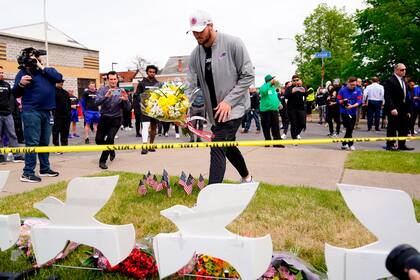 Josh Allen, jugador del equipo de fútbol americano Buffalo Bills, deposita flores en el escenario de la masacre del sábado pasado en Buffalo, Nueva York, 18 de mayo de 2022. (AP Foto/Matt Rourke)