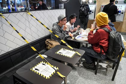 Jóvenes en un restaurante de comida rápida junto a mesas separadas en el centro de Estocolmo, el 12 de noviembre de 2020