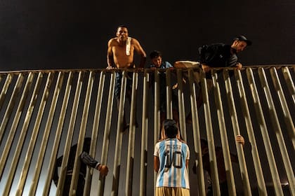 Jóvenes marroquíes, uno con la camiseta de Messi, intentan saltar la cerca fronteriza