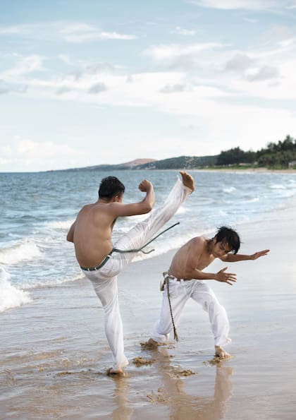 Jóvenes practicando capoeira en la playa.