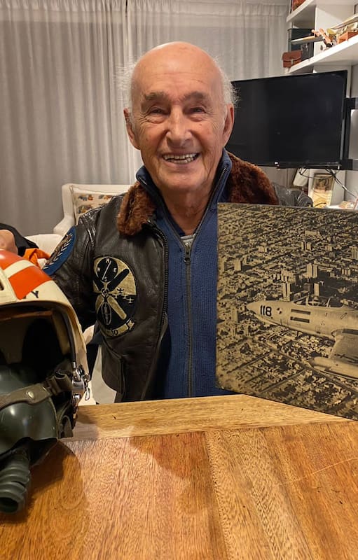 Juan Maria Pechar en su hogar junto a uno de sus cascos de aviador naval que utilizó durante su permanencia en la Aviación Naval Norteamericana, su campera de vuelo y una imagen muy especial. (Gentileza Federico Pechar).