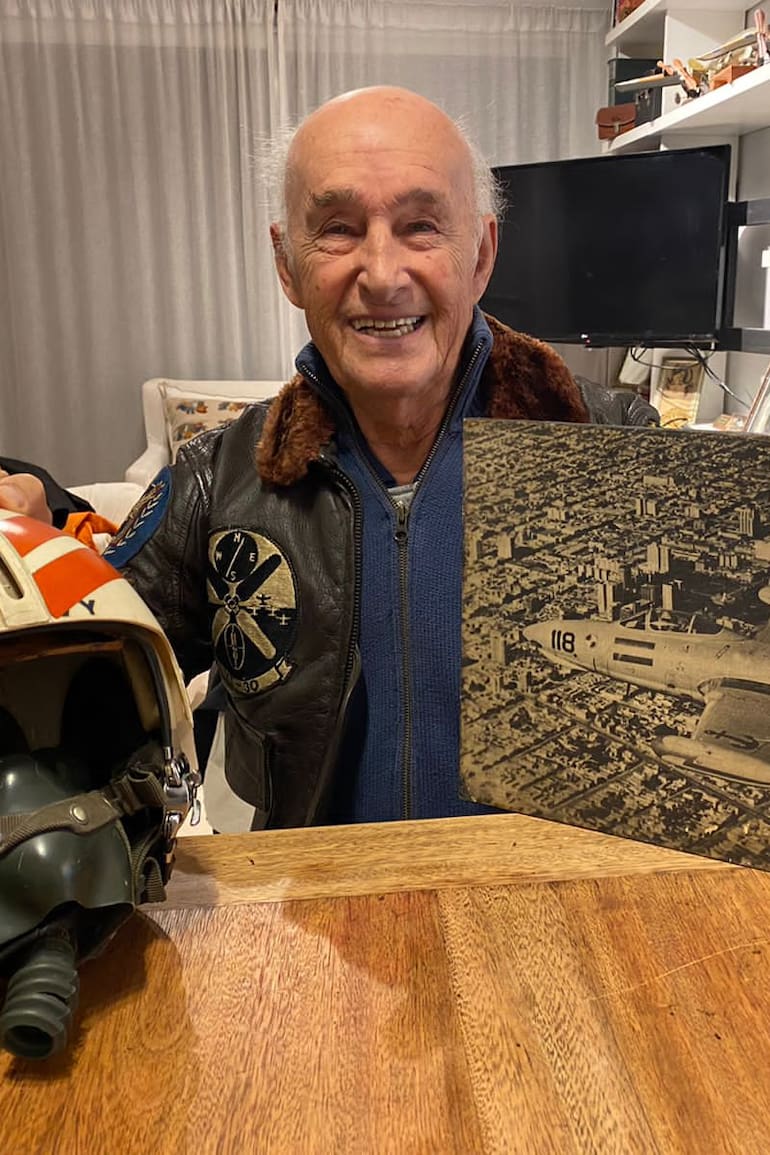 Juan Maria Pechar en su hogar junto a uno de sus cascos de aviador naval que utilizó durante su permanencia en la Aviación Naval Norteamericana, su campera de vuelo y una imagen muy especial. (Gentileza Federico Pechar).