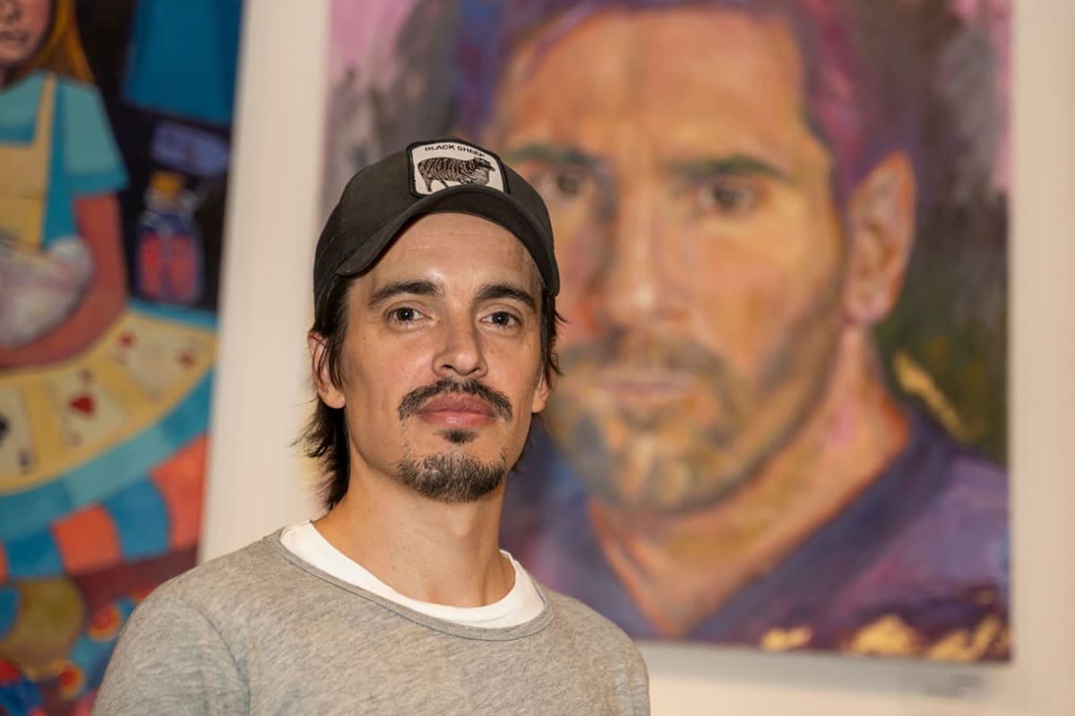 Juan Rivière delante del retrato en el que inmortalizó a Lionel Messi; la pintura será exhibida en la Casa Argentina de la capital francesa hasta el 10 de noviembre