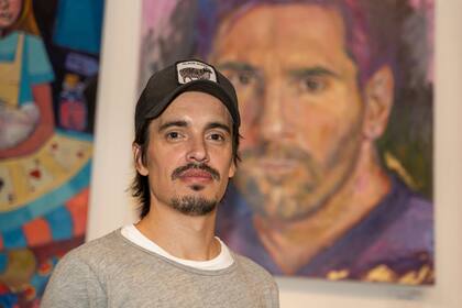 Juan Rivière delante del retrato en el que inmortalizó a Lionel Messi; la pintura será exhibida en la Casa Argentina de la capital francesa hasta el 10 de noviembre