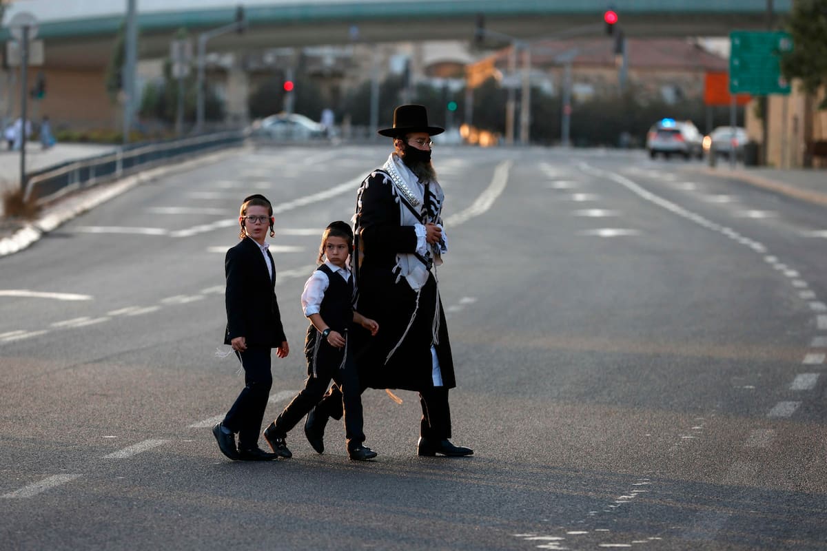 Judíos ultraortodoxos con máscaras protectoras debido a la pandemia de COVID-19, caminan por una calle vacía de camino a la sinagoga para las oraciones de Rosh Hashaná (Año Nuevo judío) en Jerusalén