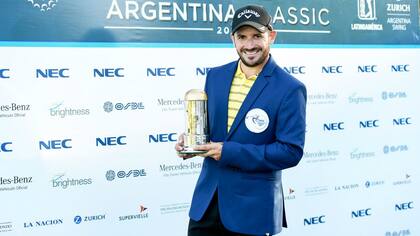 Julián Etulain, con el tradicional saco azul y el trofeo