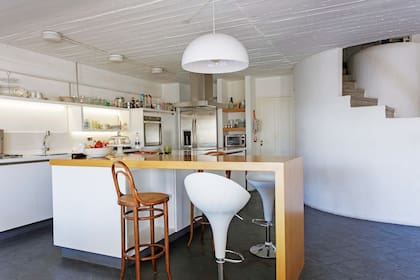 Junto a la barra, mix de banquetas: antiguas de madera con esterilla y modernas ‘Candy’ en blanco (Falabella).