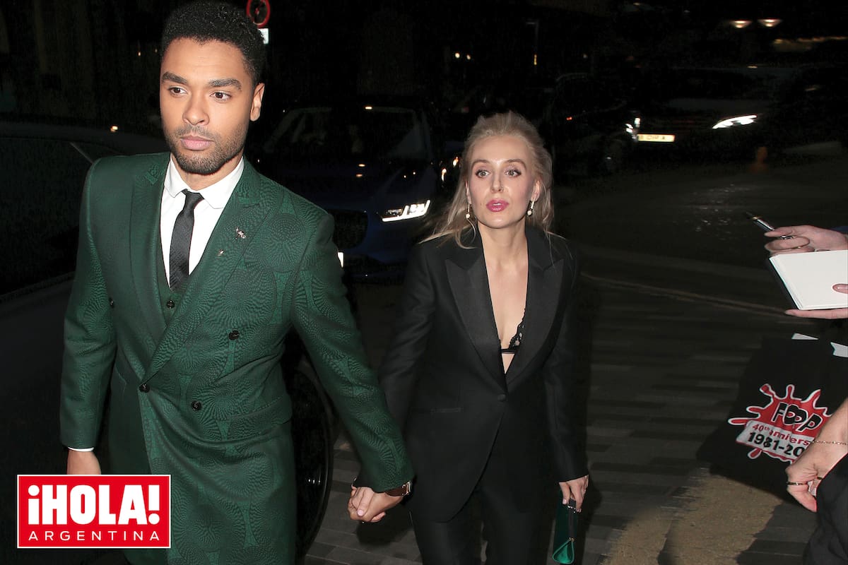 Junto a su novia, Emily Brown, con looks combinados: él vistió un elegante traje de chaqueta color verde botella, y ella un traje sastre negro con una cartera de mano verde, que parecía elegida para estar a juego con Regé-Jean