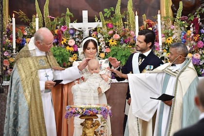Junto al obispo Johan Dalman y el párroco de la Royal Court Parish, Michael Bjerkhagenen, en plena ceremonia. Se derramó sobre el bebé agua de una fuente de Öland, una tradición que comenzó en la familia real sueca con el bautismo de la princesa Victoria, heredera del trono.