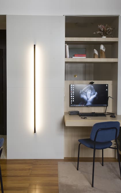 Junto al pequeño escritorio, aplique de pared lineal con luz rasante (Huup).