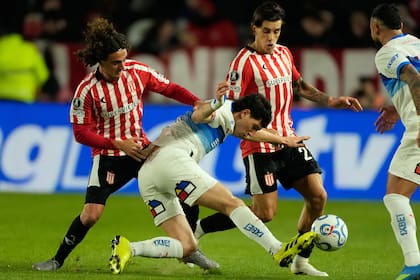 Justo Giani intenta controlar ante Gastón Benedetti y Alexis Castro; Estudiantes pasó de la celebración por una tempranera ventaja al descontento por el empate, a falta de diez minutos